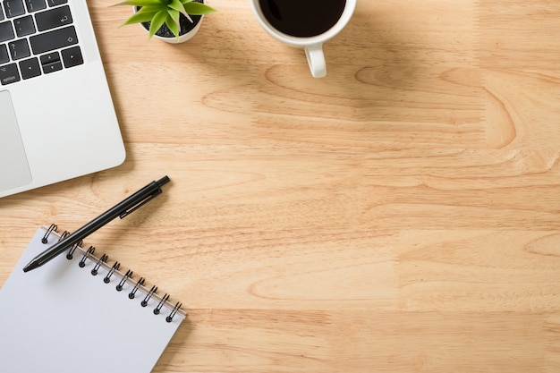 Foto flay lay, bovenaanzicht kantoor tafel bureau met laptop, toetsenbord, notitieblok, koffie, pen en groene plant