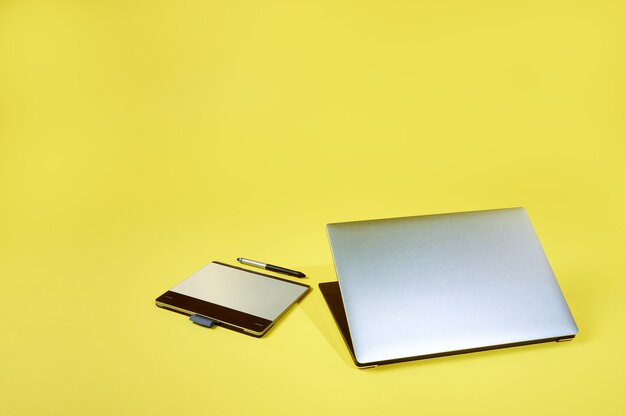 Flay lay composition of a silver grey laptop lying near a graphics tablet isolated.