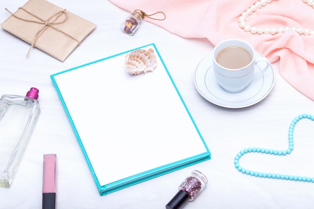 Flay lay of freelancer workspace desk with copy space. Coffee, paper blank, lip gloss, jewelry.