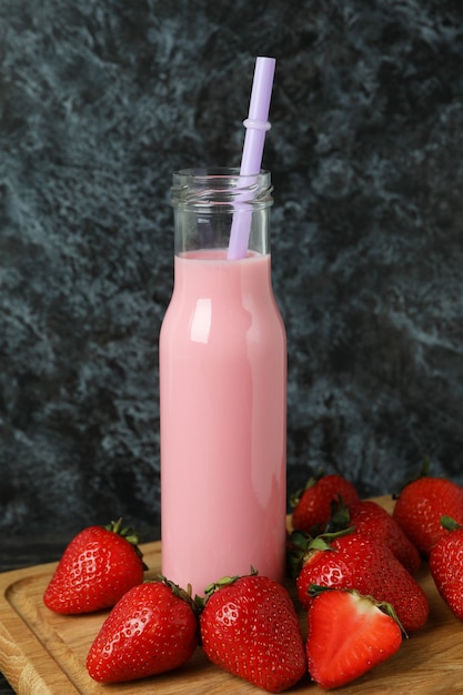 Fles aardbeienmilkshake en ingrediënten op houten tafel