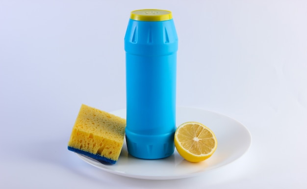 Fles afwasmiddel en citroen, spons in plaat. Afwassen concept