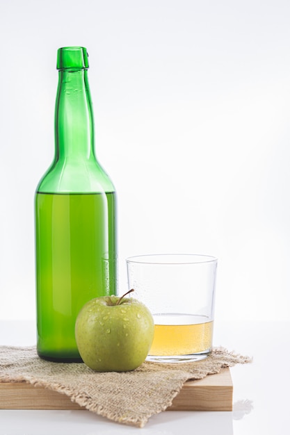 Fles Asturische cider met glas en appel.