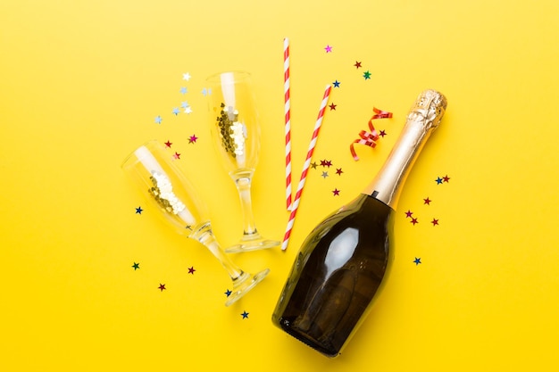 fles champagne met glazen en kleurrijke confetti op gekleurde achtergrond top view flay lay