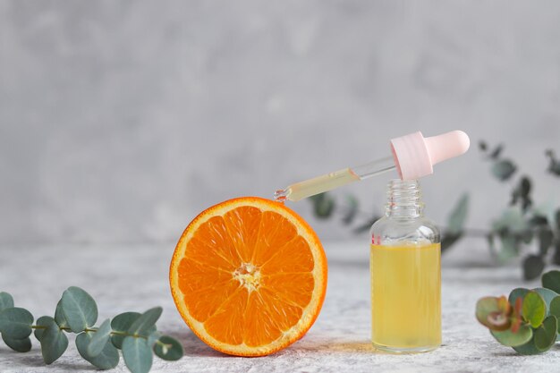 Foto fles cosmetisch huidverzorgingsserum met druppelaar sinaasappel en eucalyptus etherische olie met vitamine c
