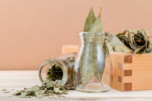 Fles droge baaibladeren met selectieve nadruk op houten achtergrond.