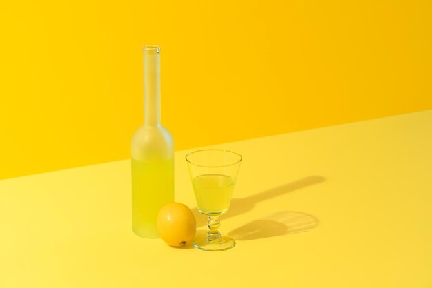 Foto fles en glas citroen likeur limoncello op een gele achtergrond italiaanse drank gemaakt met citroenen