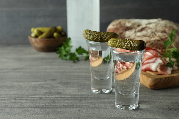 Fles en shots wodka en verschillende snacks op grijze tafel