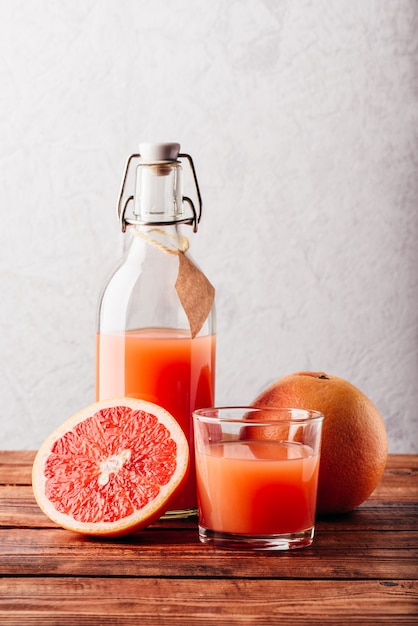 Fles grapefruitsap met glas en fruit op houten oppervlak