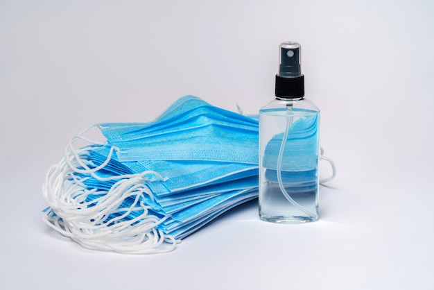 fles lotion, ontsmettingsmiddel of vloeibare zeep en beschermend masker over lichtgrijze tafel