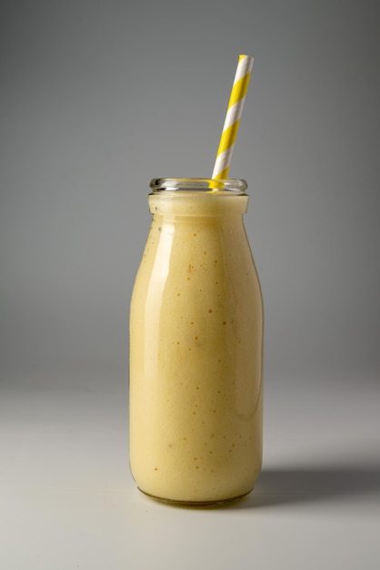 Fles mango banaan en yoghurt smoothie met een rietje