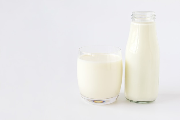 Fles melk en glas melk op een witte achtergrond