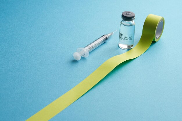 Foto fles met covid-19-vaccin en injectiespuit met gele tape voor kopieerruimte