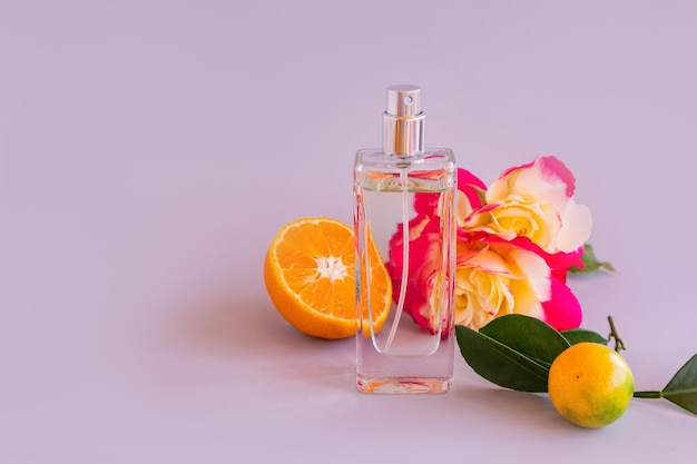 Fles met damesparfum tegen de achtergrond van een chique roos en mandarijnvruchtenpresentatie van de geur een vooraanzicht van een kopieerruimte