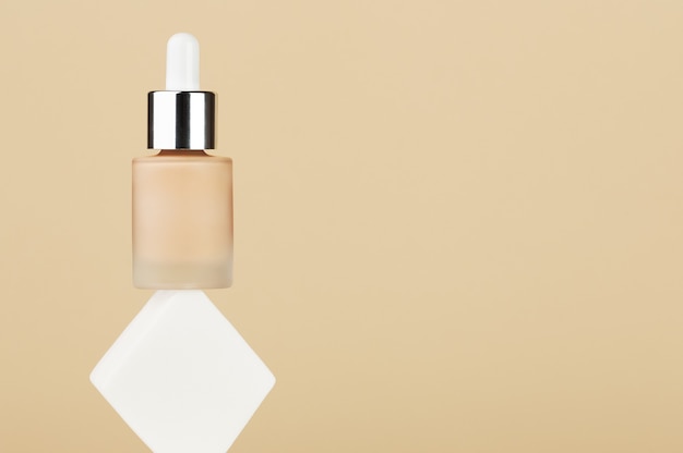 Fles met foundation vloeibare beige crème balans op witte vierkante spons. professioneel make-upproduct voor een perfecte teint. damesaccessoires, basisschoonheidsproduct, primer, concealer. ruimte kopiëren.