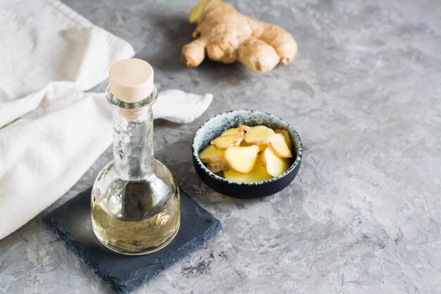 Fles met natuurlijk gember serum en gehakt gember in een kom op de tafel natuurlijke verzorging cosmetica