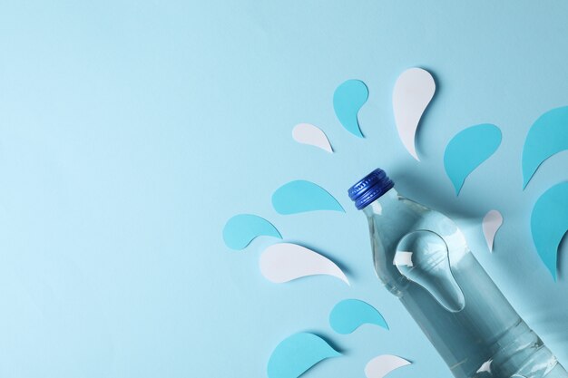 Fles met water op decoratieve blauwe, bovenaanzicht