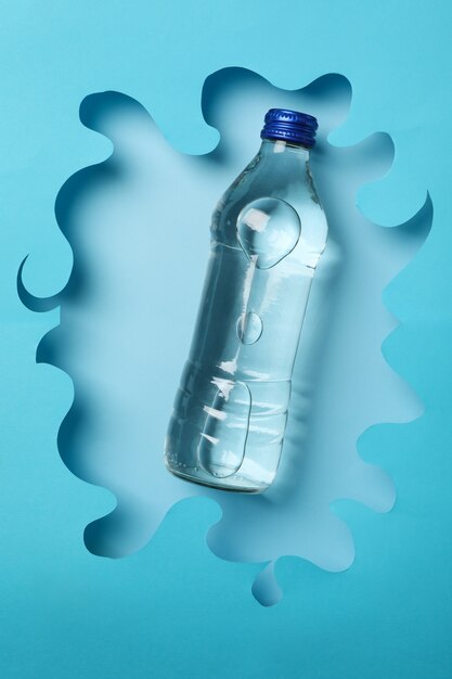 Fles met water op decoratieve blauwe, bovenaanzicht