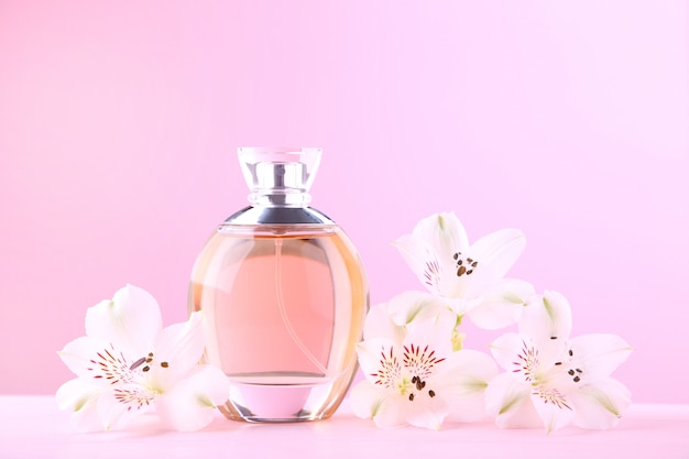 Fles parfum met bloemen op roze