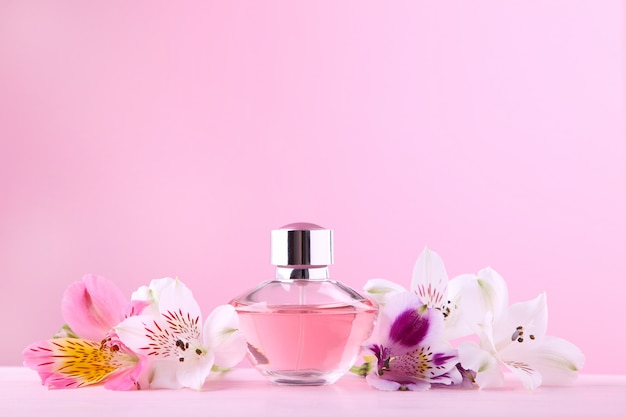 Fles parfum met bloemen op roze