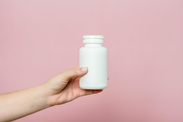 Fles pillen of vitamines in de hand van de vrouw Witte verpakking voor uw pil of capsule en supplement