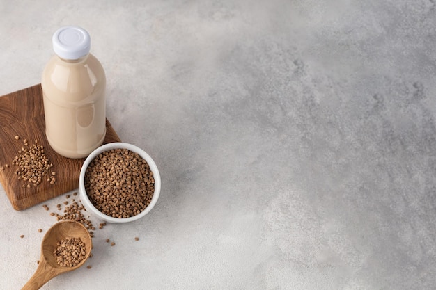 Fles plantaardige melk van boekweit met een ingrediënt in een kom op een lichte achtergrond