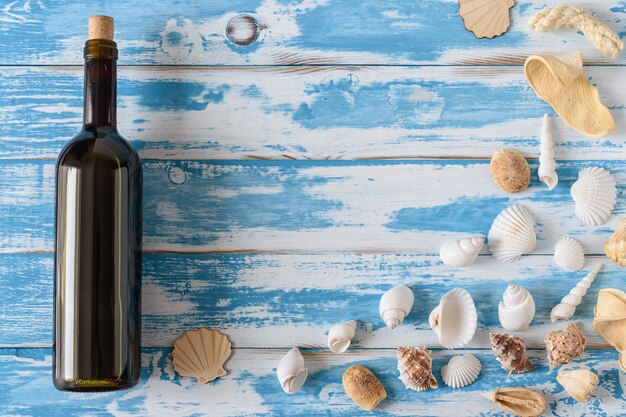 Fles rode wijn op vintage blauwe houten plank met schelpen