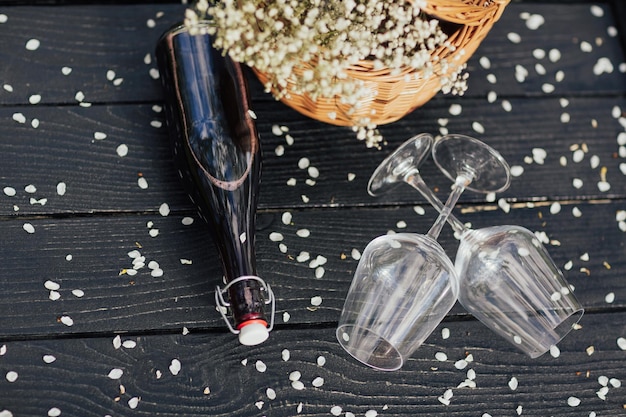 Fles rode wijn twee glazen en mand met bloemen op zwarte houten achtergrond