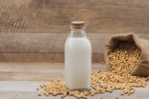 Fles sojamelk en soja op houten tafel