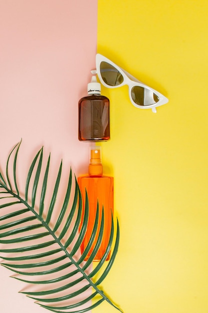 Fles sunblock op heldere vierkante gele en roze achtergrond Het concept van het resort op zee zomertijd Bovenaanzicht plat lag minimalisme kopieerruimte