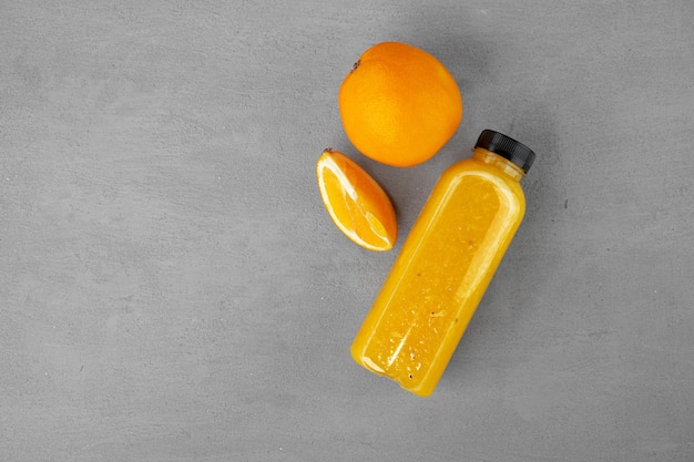 Fles vers geperst sinaasappelsap op grijze achtergrond, kopieer ruimte