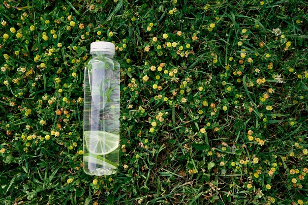 Fles water ligt op het groene gras tussen de wilde bloemen