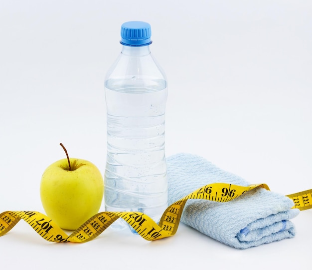 Fles water met appel met fitnesshanddoek en meetlint