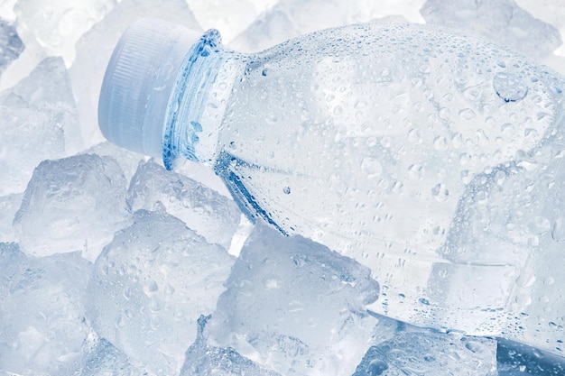 Fles water op ijsblokjes close-up