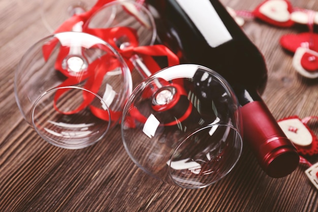 Fles wijn en glazen met handgemaakte harten op houten achtergrond, close-up