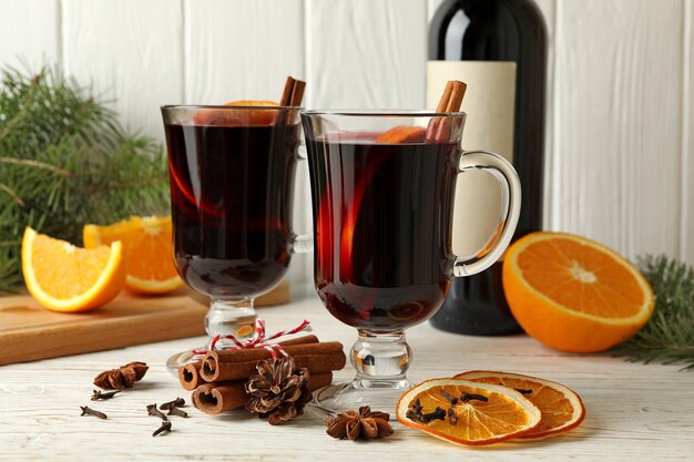 Fles wijn, kopjes glühwein en ingrediënten op houten