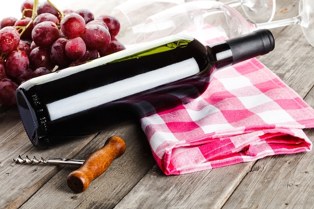 Foto fles wijn kurkentrekker en druiven op houten tafel