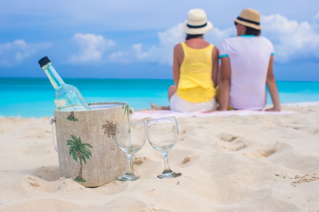 Fles witte wijn en twee glazen achtergrond gelukkig paar op zandstrand