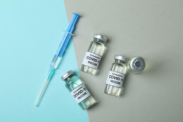 Flesjes Covid - 19 vaccin en spuit op tweekleurige achtergrond