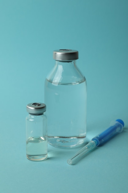 Flesjes met Covid - vaccin 19 en spuit op blauwe achtergrond