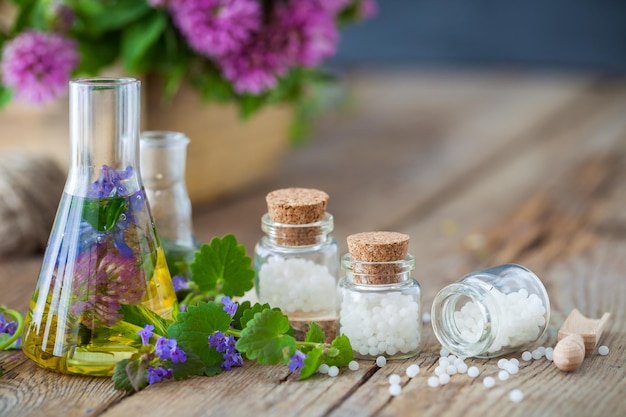 Flesjes tinctuur of infusie van gezonde kruiden flessen homeopathie bolletjes en gezonde kruiden op tafel Alternatieve geneeskunde concept