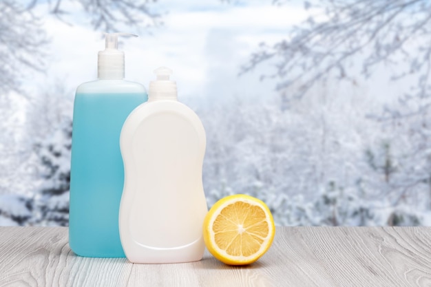 Flessen afwasmiddel en citroen met de winter op de achtergrond