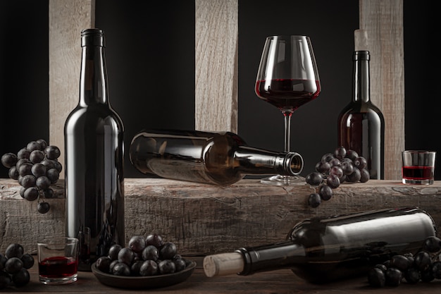 Flessen en glazen Spaanse rode wijn en druiven op houten voet