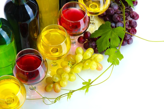 Flessen en glazen wijn en rijpe druiven die op wit worden geïsoleerd