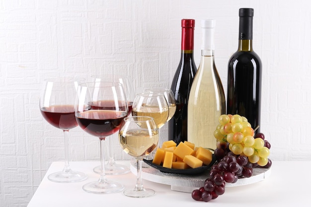 Flessen en glazen wijn, kaas en rijpe druiven op tafel in de kamer