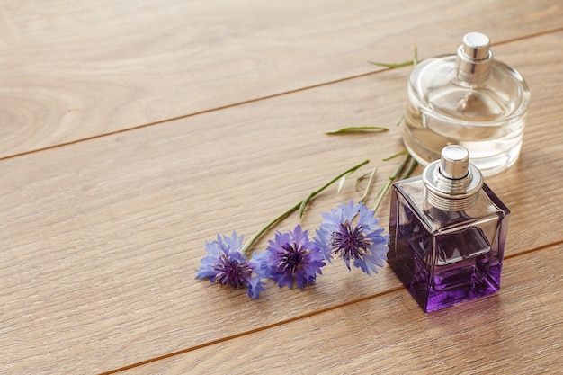 Flessen parfums met knoopkruidbloemen op houten planken