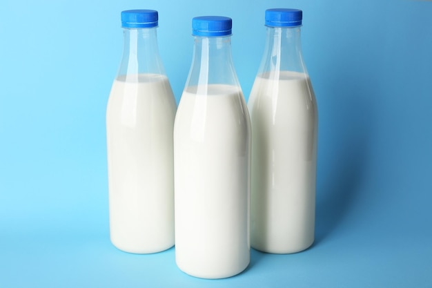 Flessen smakelijke melk op blauwe achtergrond