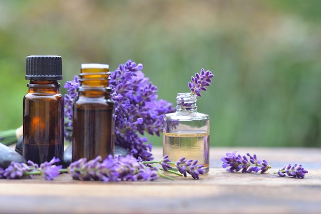 Flessen van etherische olie onder lavendel bloem gerangschikt op een houten tafel in de tuin