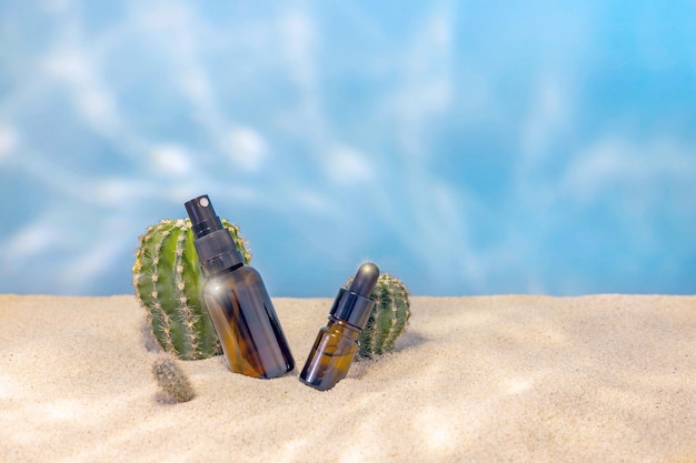Flessen voor cosmetica zand en cactussen op een blauwe achtergrond met lichte highlights
