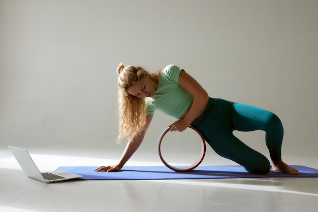 Foto flexibel jong meisje doet gymnastiek flexibiliteit en strekken met behulp van een yoga wiel online op een witte achtergrond