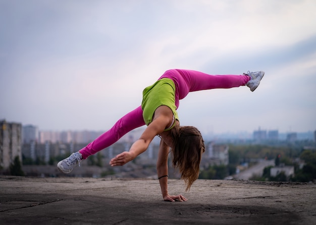Flexibel meisje houdt aan de ene kant evenwicht in splitsing op het stadsgezicht achtergrondconcept van potentieel